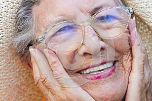 Close up of old senior woman smiling and holding her face with hands. Happiness and youthness concept lifestyle with old female