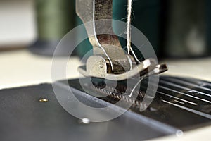 A close-up of an old sewing machine with a multicolored needle and thread on a tailor`s desk, perfect for presentation.