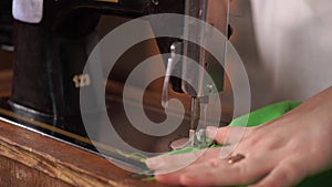 Close up of old sewing machine with women's hands on table. Woman stitching fabric, using soviet sewing machine.