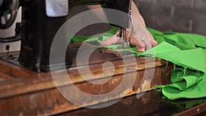 Close up of old sewing machine with women`s hands on table. Woman stitching fabric, using soviet sewing machine.