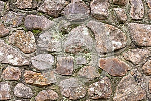 A close up of an old stone wall, with little bits of moss and weeds, perfect for backgrounds and abstracts