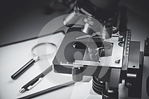 Close up of old vintage of microscope with metal lens, science equipment, pen, pencil and magnifying glass at at laboratory