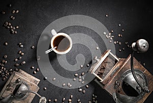 Close up of old vintage retro grinder with cup of black coffee and coffee beans top view on black background with copy space