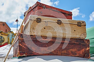 Close-up of old vintage travel suitcases fastened to the roof of a car with a rope and in the background a lovely blue sky with cl