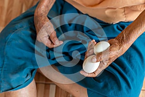 Close-up of the old woman's hand Poor Thai grandmother holds a large white duck egg for dinner. Pure egg