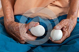 Close-up of the old woman's hand Poor Thai grandmother holds a large white duck egg for dinner. Pure egg whites