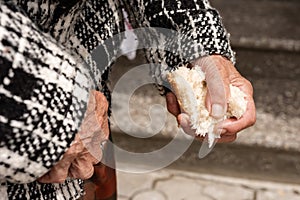 close-up of the old woman& x27;s hands, a piece of broken bread in the woman& x27;s hands. Poverty and starving pensioners