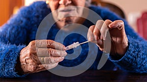 Close-up of old woman taking a self swabbing home tests Covid19 with antigen kit