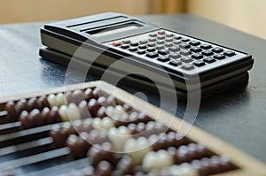 Close-up old wooden abacus and a calculator on a black table