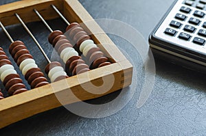 Close-up old wooden abacus and a calculator on a black table