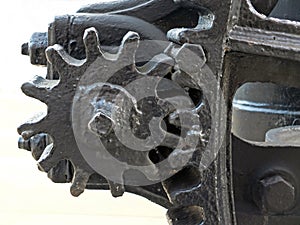 Close up of old worn black painted large cog wheels with gear teeth on obsolete industrial machinery