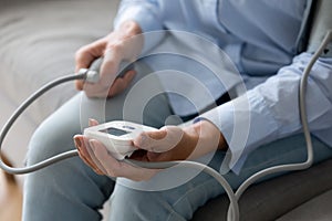 Close up older woman checking blood pressure with digital tonometer