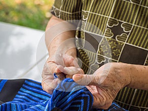 Close up of older woman hands using razor to mend a cloth