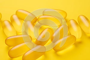 Close up Omega 3 capsules on yellow background. Fish oil softgels. Supplement food vitamin D capsules