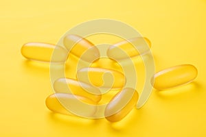 Close up Omega 3 capsules on yellow background. Fish oil softgels. Supplement food vitamin D capsules