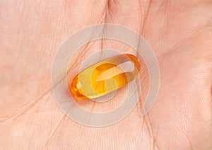 Close up of omega 3 fish oil capsule in human hand.