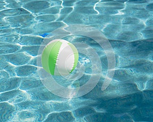 Close-up one bright green beach ball in swimming pool sunny day