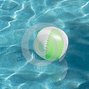 Close-up one bright green beach ball in swimming pool sunny day