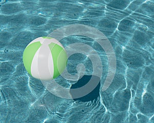 Close-up one bright green beach ball in swimming pool sunny day