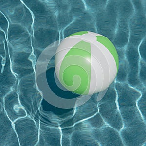 Close-up one bright green beach ball in swimming pool sunny day