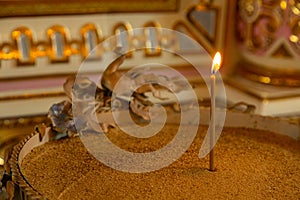 Close-up of one burning candle standing in cup with sand inside christian church