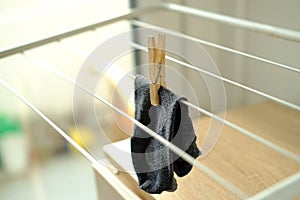 Close-up of one dark gray men`s sock hangs lonely on wire room dryer, home chores concept, missing socks, gentle hand washing of