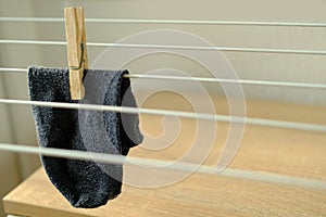 Close-up of one dark gray men`s sock hangs lonely on wire room dryer, home chores concept, missing socks, gentle hand washing of