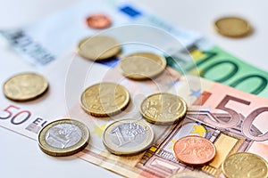 Close up of one euro coin surrounded by different coins and 100 and 50 Euro banknotes