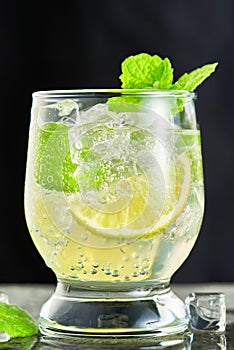 Close-up of one glass with a mojito cocktail on a grey background. Vertical shot from a low angle