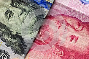 Close up of one hundred Dollar and 100 Yaun banknotes with focus on portraits of Benjamin Franklin and Mao Tse-tung/USA vs China t