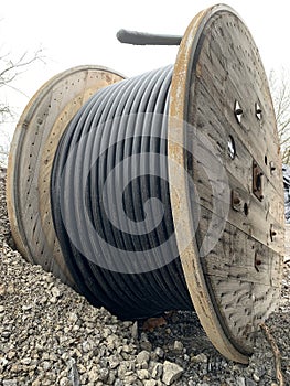 Close-up of one large wooden reel with a black electrical cable outside on a construction site in Germany in dull weather. Side