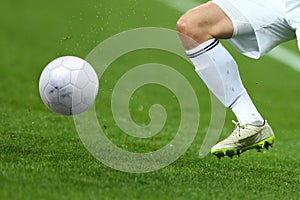 Close up one leg and feet of football player with the ball