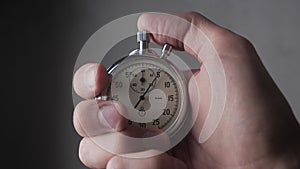 Close-up of one person starting up a stopwatch at grey background. 4K, 10 BIT, 4:2:2.