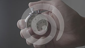 Close-up of one person starting up a stopwatch at grey background. 4K, 10 BIT, 4:2:2.