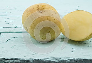 Close up of one potato and slice on rustic sea green wood backgr