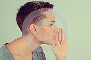 Close up One woman telling a secret holding hand near mouth secrecy gesture isolated green background wall. Horizontal image