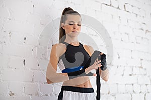 Close up of one young woman wrapping hands with black boxing wraps in gym practice boxing indoor working out fitness