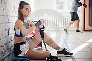 Close up of one young woman wrapping hands with black boxing wraps in gym practice boxing indoor working out fitness