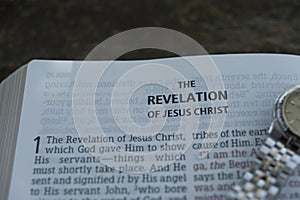 Close-up of open Bible in Revelation of Jesus Christ in chapter 1 with clock. Copy space.