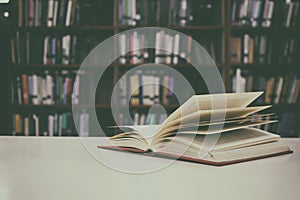 Close up of open book on desk with vintage filter blur background