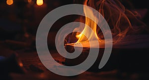 Close-up of open book with flames burning on the pages in dark environment