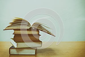 Close up of open book and Stack of books on desk with vintage filter blur background