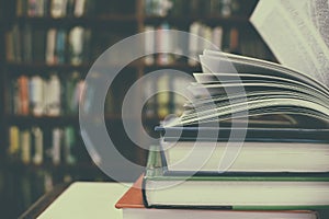 Close up of open book and Stack of books on desk with vintage filter blur background