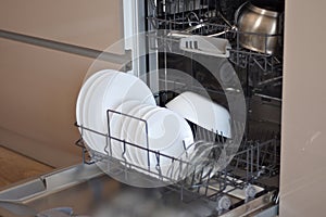 close up open dishwasher with clean white plates