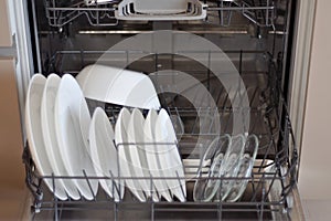 close up open dishwasher with clean white plates