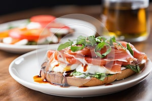 close-up of an open-face prosciutto sandwich and caprese salad