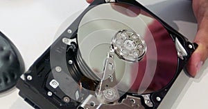 Close-up of an open hard disk drive in the hands of a technician