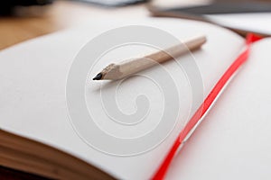 Close-up of open notebook and pencil, red book-mark