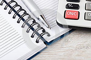 Close up of open notepad, ballpoint pen and electronic calculator