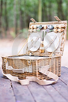 Close up of an open picnic basket over wooden table in the park.